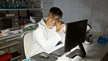 Young hispanic man scientist using computer smiling at laboratory