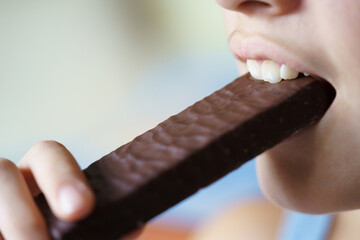 Crop anonymous teenage girl eating delicious chocolate protein bar