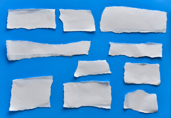 Various torn pieces of white paper, stickers on a blue background.