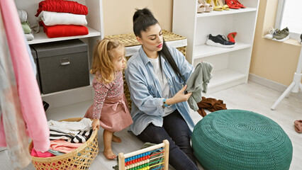 Mother and daughter organizing wardrobe together in a bright room, depicting family and domestic life.
