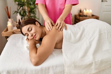 Obraz na płótnie Canvas Young beautiful hispanic woman lying on table having back massage at beauty salon