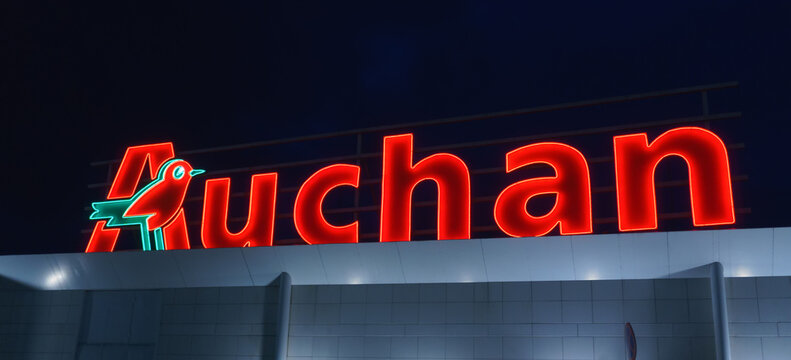 Auchan store sign glows red in the evening