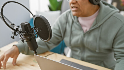 Middle-aged man with headphones speaking into a microphone in a radio studio setting