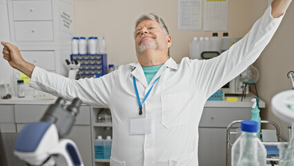 Middle-aged man in labcoat stretching in a laboratory, displaying contentment and a break from work.