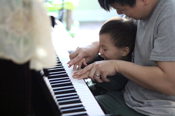 daddy having a bonding moment with his son playing a piano