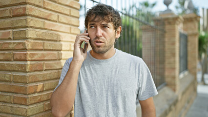 Portrait of a handsome, young guy, with blond beard talking on his phone, deep in concentration....