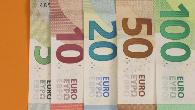 Euro banknotes transition on orange paper background. 4K stop motion animation.