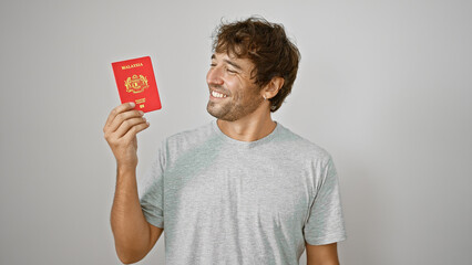 Confident young man exuding joy, proudly flaunts his malaysian passport, standing isolated against...