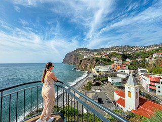 Tourist woman looking at Praia de Vigario in Camara de Lobos on Madeira island, Portugal, Europe....