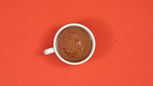 Retro cup filled with tea on red background. Top view, 4K stop motion animation.
