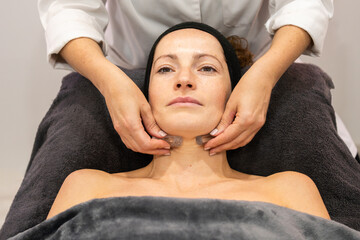 Female beautician massaging neck of client with stones