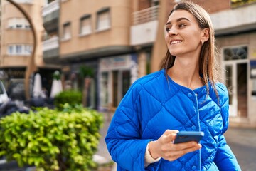 Fototapeta premium Young caucasian woman smiling confident using smartphone at street