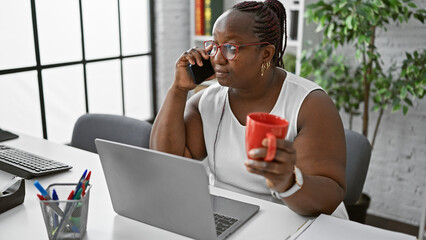 Braided african-american woman boss, indulging in her morning espresso, engaged in serious work...