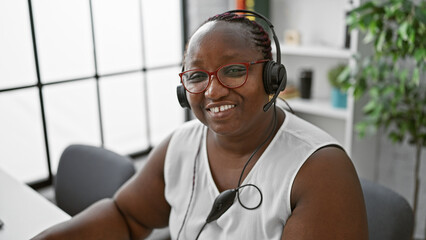 Confident african american woman happily working as a business executive, wearing a headset, and...