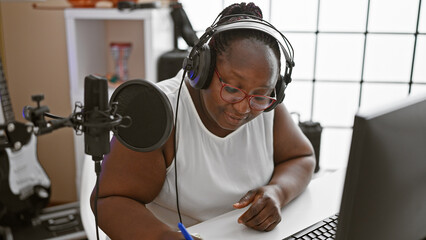 Serious african american woman musician in braids, composing a soul-stirring song in a music...