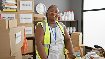 Confident african american woman volunteer, smiling and standing proud at charity center. working...