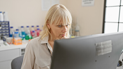 Focused blonde woman working at computer in a laboratory setting.