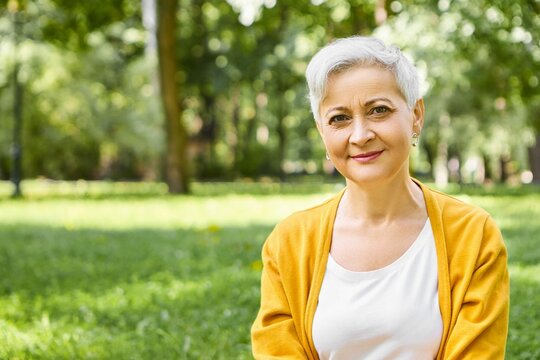 Summertime Mature People Age Leisure Concept Outdoor Shot Stylish Caucasian Woman Pensioner With Gray Short Hair Wearing Yellow Cardigan Relaxing Wild Nature With Smile