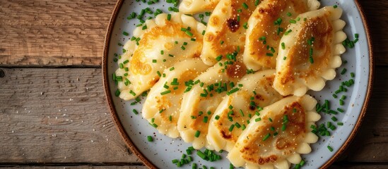 A close-up top view of a white plate filled with pierogi pasta covered in savory sauce. The...