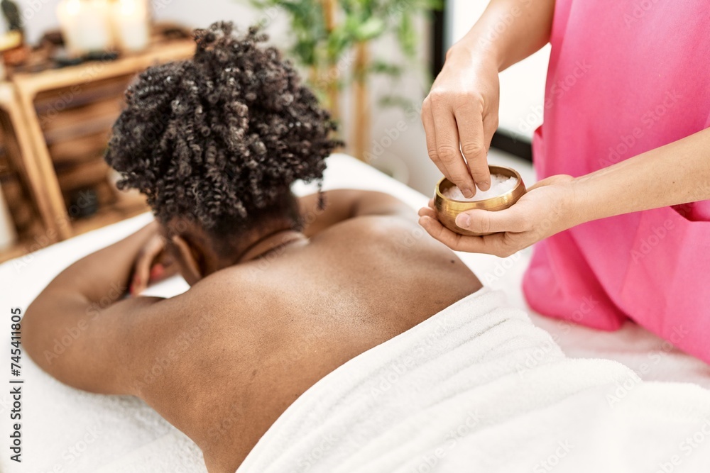 Sticker african american woman lying on massage table having facial treatment at beauty salon