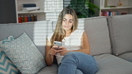 Beautiful couple using smartphone sitting on sofa at home