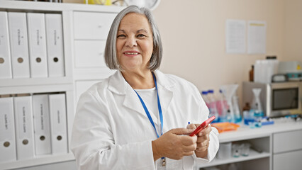 Smiling senior woman scientist with grey hair in white lab coat indoors at laboratory