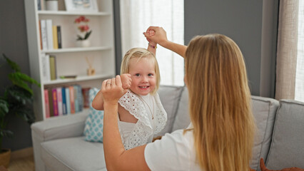 Confident caucasian mother and daughter bonding over giggles while jumping on sofa, radiating joy at their relaxing home