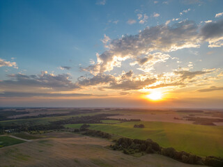 Obraz premium A drone photo of a young green wheat field during sunset. Aerial view of a farmer's field. Abstract patterns and straight lines on farmland.