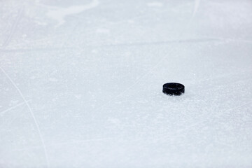 The hockey black puck is on the ice. Selective focus