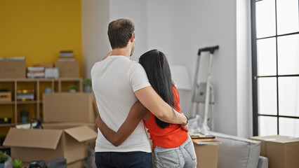 Fototapeta premium Beautiful couple standing backwards hugging each other at new home