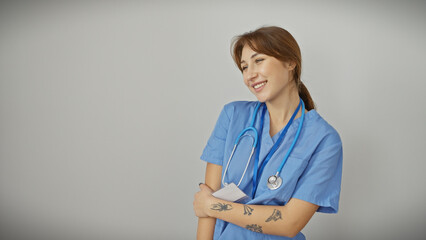 Smiling caucasian nurse in blue scrubs with stethoscope against a white background