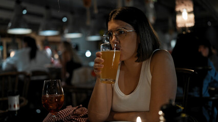 Young beautiful hispanic woman drinking beer at the restaurant