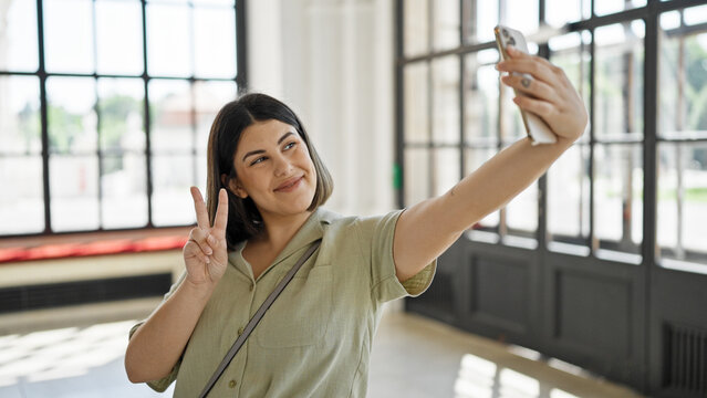 Young beautiful hispanic woman taking selfie with smartphone at new home
