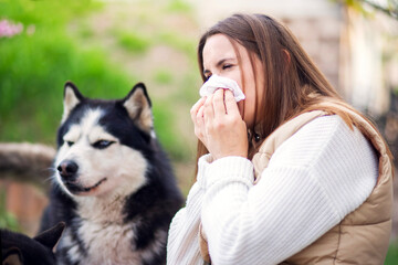 Woman Suffering Allergy Next to Husky Dog