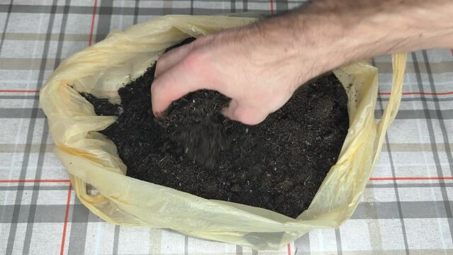 A hand of a gardner mixing potting soil with water