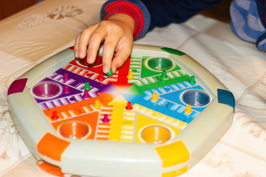 Hand of a small child playing Parcheesi.