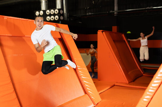 Sports guy training to do jumps in trampoline center, jumping sideways and up. High quality photo