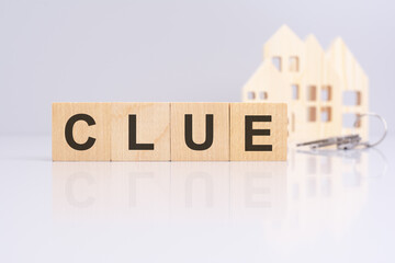 wooden cubes on a table with text CLUE, model house and keys on background. concept of business, financial, investment, economy. gray background