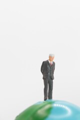 miniature figurine of a businessman on the top of a world globe