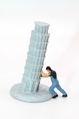 miniature figurine of a man pushing the Pisa tower