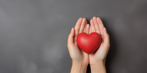 Obraz premium Woman's hands holding red heart on grey background. Valentine's day, health care, world heart day, world health day.