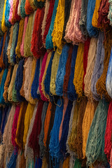 Colorful hanging fiber threads yarn for weaving handcrafted rugs, scarfs, and blankets in souk media Marrakesh, Morocco 