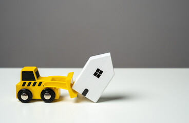 A bulldozer demolishes a house. Toy figures. Territory clearing service. The bulldozer intends to...