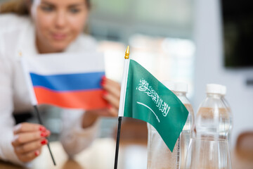 Little flag of Saudi Arabia on table with bottles of water and flag of Russia put next to it by...