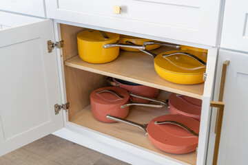 Colorful cookware in kitchen cabinet