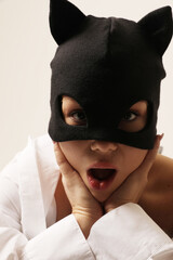 Emotional young woman wearing black cat mask posing on white background. Close-up.