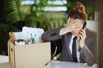 sad woman worker in green office talking on phone
