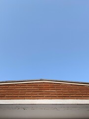 minimalist photo of house roof with a wall and blue sky