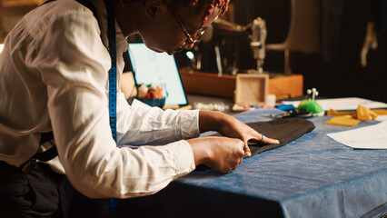 Tailor measuring fabric in workshop, checking material measurements, custom made clothing line. Employee working on luxury fashion collection in fashion atelier. Handheld shot. Close up.