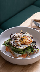 A plate of waffles and salmon with egg and seeds on wooden restaurant table